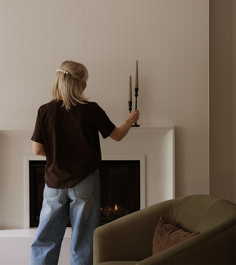 Réalisations en design d’intérieur à Mirabel : mise en scène d’un foyer contemporain avec manteau blanc, mur texturé et fauteuil vert olive, illustrant l’attention portée aux détails par Atelier Ancrage.